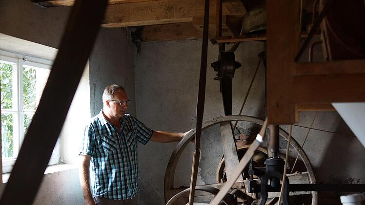 Benno Zellhan zeigt, von wo aus die ganze Mühle über Transmissionsriemen angetrieben wird. Foto: Arkadius Guzy