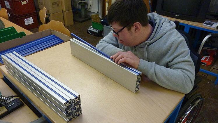 Johannes Büttner steckt Kunststoffleisten in Profile.  Foto: Lebenshilfe