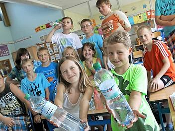 Emily (10) und Daniel (9) aus der Klasse 4a der Grundfelder Schule zeigen es: Momentan sollte man dort, wie auch in Vierzehnheiligen oder Wolfsdorf, das Wasser nicht direkt aus der Leitung trinken, sondern abgepacktes Mineralwasser nehmen. Man kann isch aber auch mit abgekochtem Wasser behelfen.  Foto: Tobias Kindermann