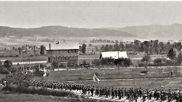 Die Festteilnehmer beim Überqueren der Eisenbahn in Stockheim. Eine Eisenbahnbrücke wurde erst 1905 erbaut. Gut erkennbar die evangelische Schule von 1899, rechts daneben das Bernschneidershaus.Repro: GF