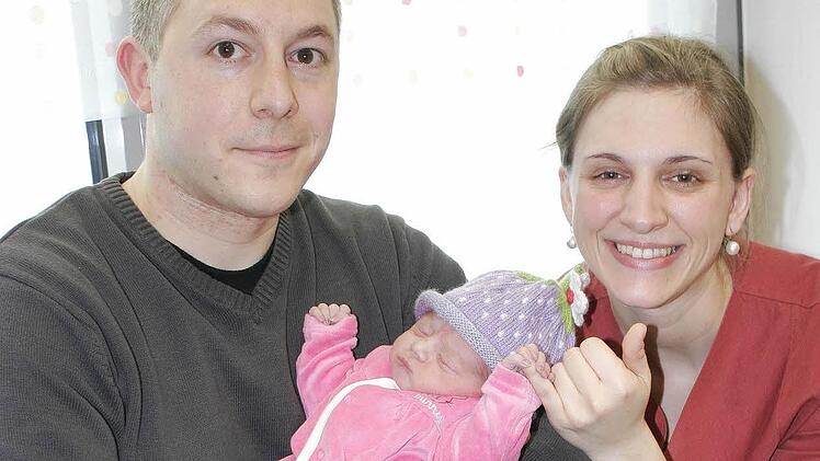 Auch wenn die kleine Amalia dabei schläft: Sie stand am Donnerstag beim offiziellen Fototermin im Mittelpunkt. Exakt um 8.39 Uhr erblickte sie am 2. Januar als erste neue Erdenbürgerin im Landkreis Haßberge im Jahr 2014 in der Station Gynäkologie/Geburtshilfe im Haus Haßfurt der Haßbergkliniken das Licht der Welt. Über die Kleine freuen sich der glückliche Papa Sebastian und Hebamme Anne Bedruna während sich Mama Simone (34) noch von der anstrengenden Geburt erholte. Foto: Ralf Naumann