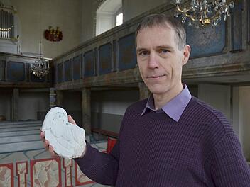 Pfarrer Ronald Henke zeigt den Flügel, der einem der Engel an der Kirchendecke verloren gegangen ist und auf den Boden stürzte. Fotos: Rainer Lutz