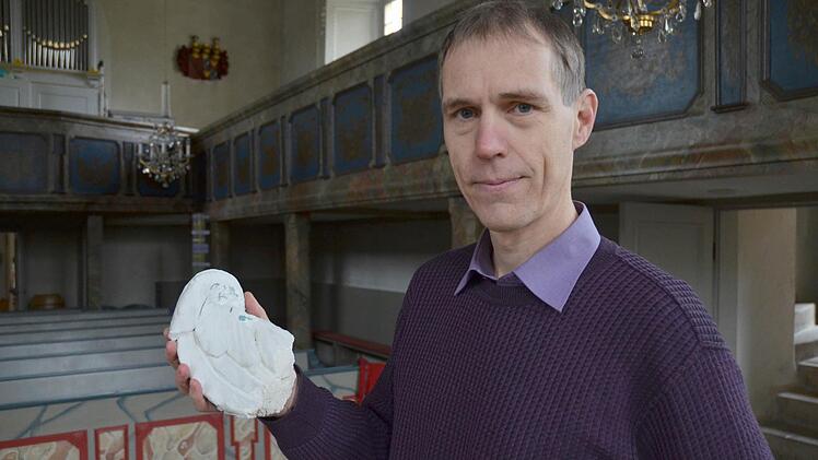Pfarrer Ronald Henke zeigt den Flügel, der einem der Engel an der Kirchendecke verloren gegangen ist und auf den Boden stürzte. Fotos: Rainer Lutz