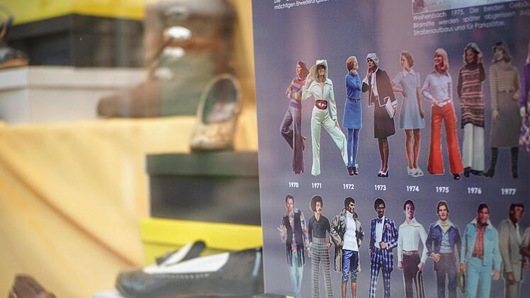 Diese Tafel in einem Schaufenster zeigt die zeitgenössische Mode in den 1970er Jahren.