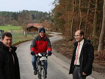 Bürgermeister Carsten Joneitis (links) und Amtsleiter Anton Hepple (rechts) freuen sich über den ersten Radfahrer - Siegfried Jeltsch - auf dem neuen Wirtschaftsweg am Lerchenholz. Foto: Barbara Herbst