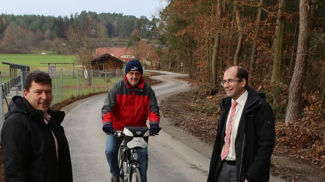 Bürgermeister Carsten Joneitis (links) und Amtsleiter Anton Hepple (rechts) freuen sich über den ersten Radfahrer - Siegfried Jeltsch - auf dem neuen Wirtschaftsweg am Lerchenholz. Foto: Barbara Herbst