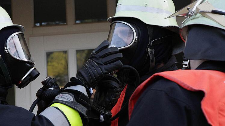 Die Einsatzkräfte helfen sich beim Anlegen der Atemmasken.