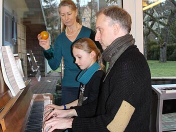 Cornelia Stenglein begleitet Helen Haas und Holger Fischer rhythmisch mit einer Rassel. Dabei verfolgt sie genau, wie die beiden spielen. Foto: Helke Renner