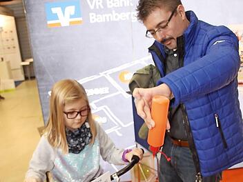 Am Stand der Raiffeisenbank sorgte Messe-Promotor Jörg Burghardt für Hochbetrieb. Er hatte sein "Mal-Fahrrad" mitgebracht und das wollten nicht nur die Kleinen ausprobieren. Emelie Söllner achtete genau darauf, dass Papa Klaus (rechts) alles richtig machte. Foto: Rüdiger Klein