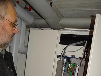 Heizkessel raus, Wärmetauscher rein: Mit der Versorgung durch die Biogasanlage haben die Nutzer in Maroldsweisach an Wohnraum gewonnen. Peter Pratsch zeigt den Steuerschrank, mit dem nun die Wärme im Haus kontrolliert wird. Foto: Johanna Eckert