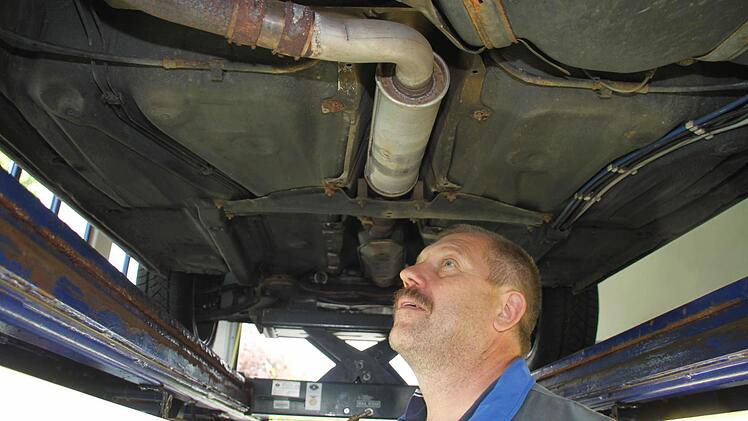 Günter Teufel prüft kritisch den Unterboden des Fahrzeugs.