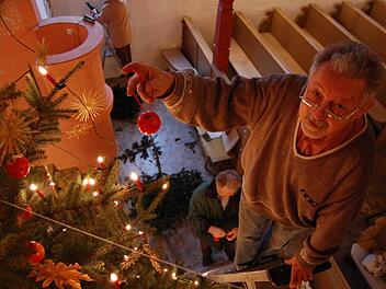 Helmut Schamberger befestigt einen Apfel nach dem anderen am Weihnachtsbaum in der Seidmannsdorfer Kirche. Fotos: Oliver Schmidt