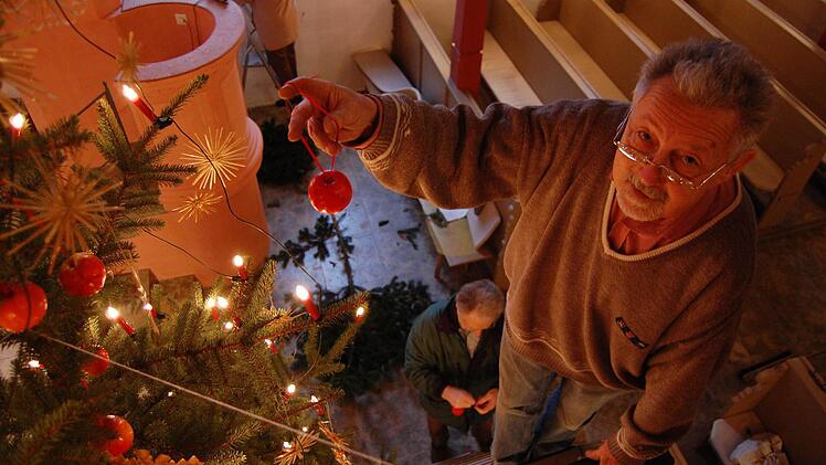 Helmut Schamberger befestigt einen Apfel nach dem anderen am Weihnachtsbaum in der Seidmannsdorfer Kirche. Fotos: Oliver Schmidt