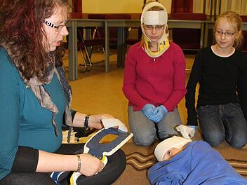 Michaela Hübner zeigt Michelle Bergeron (12) und Leonie Tulke (10), wie man einen Verletzten fachgerecht verarztet. Florian Uhl hat sich Kopfverbände anlegen lassen. Fotos: Sonja Adam