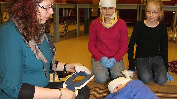 Michaela Hübner zeigt Michelle Bergeron (12) und Leonie Tulke (10), wie man einen Verletzten fachgerecht verarztet. Florian Uhl hat sich Kopfverbände anlegen lassen. Fotos: Sonja Adam