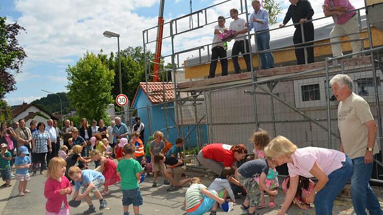 Es regnete Süßigkeiten beim Richtfest für die Erweiterung der Kinderkrippe. Auf dem Gerüst stehen (von rechts) Bürgermeister Egon Herrmann, Pfarrer Christoph Teille, Zimmerermeister Günther Stenglein, Dachdeckermeister Björn Gehring und Matthias Arndt. Foto: K.-H. Hofmann