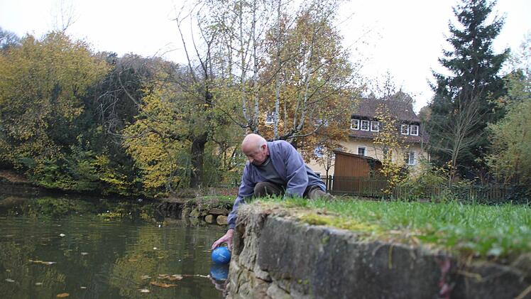Georg Berold hat bei dem niedrigen Wasserstand Mühe einen Ball aus dem Weiher zu holen.