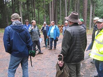 Amtsrat Jochen Dahmer (3. von links) erläutert den Teilnehmern der Waldbegehung eine geplante Pflanzung von Weißtanne und Roteiche, die man  an der Straße Richtung Singenrain ohne Zaunschutz in Lücken eines durchforsteten Altbestandes vornehmen will.