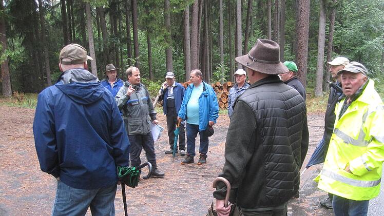 Amtsrat Jochen Dahmer (3. von links) erläutert den Teilnehmern der Waldbegehung eine geplante Pflanzung von Weißtanne und Roteiche, die man  an der Straße Richtung Singenrain ohne Zaunschutz in Lücken eines durchforsteten Altbestandes vornehmen will.
