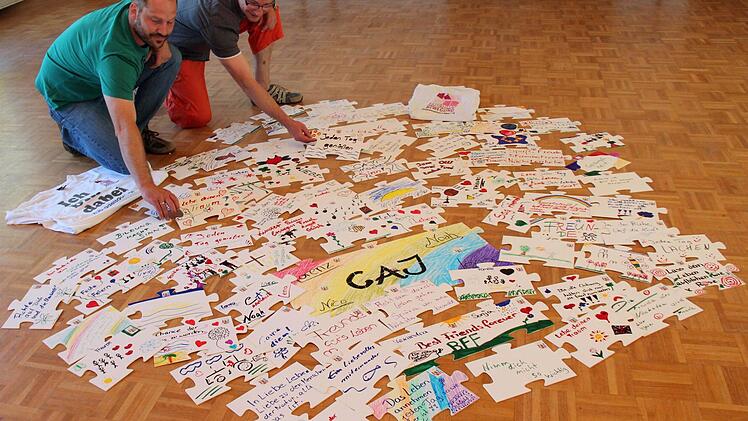 Andreas Hummel (l.) und Stefan Kirchner legen die Puzzle-Teile aus, die in Adelsdorf schon gestaltet wurden. Foto: Johanna Blum