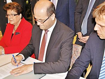 Der bayerische Finanzstaatssekretär Albert Füracker (Mitte) unterzeichnet im Beisein von Landtagspräsidentin Barbara Stamm den neuen Vertrag mit Marco Warnhoff, stellvertretender Direktor des Diözesan-Caritasverbandes Würzburg.  Fotos: Sigismund von Dobschütz