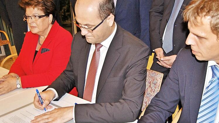 Der bayerische Finanzstaatssekretär Albert Füracker (Mitte) unterzeichnet im Beisein von Landtagspräsidentin Barbara Stamm den neuen Vertrag mit Marco Warnhoff, stellvertretender Direktor des Diözesan-Caritasverbandes Würzburg.  Fotos: Sigismund von Dobschütz
