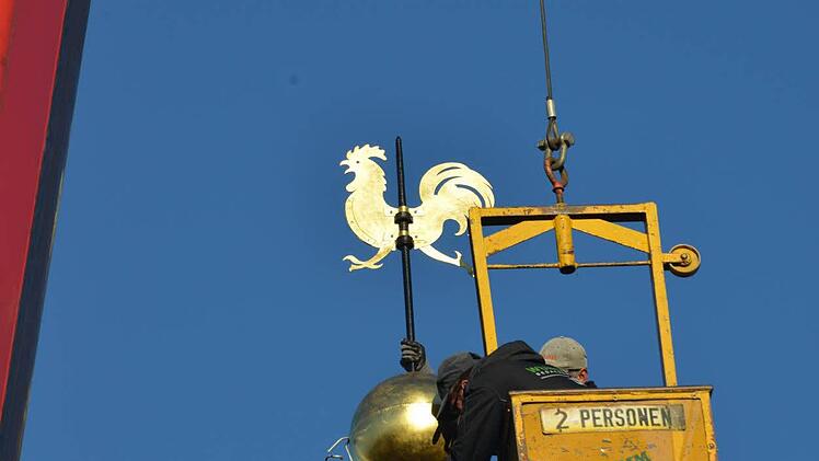 Kupferkugel und Wetterhahn - jeweils frisch vergoldet - werden montiert.  Foto: Alexander Rosenmeyer