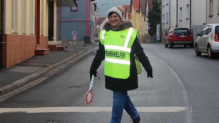 Fürs Foto hat Petra Eichholz ihre Ausrüstung nochmal angezogen: Eine hell leuchtende Verkehrshelfer-Weste, eine Winkerkelle, dazu feste Schuhe, eine warme Jacke, Handschuhe und Mütze.  Foto: Charlotte Wittnebel-Schmitz