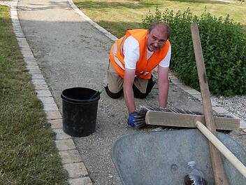 Eddi Grimm bei seiner täglichen Arbeit. Kniend zupft der "Mister Saubermann" das Unkraut aus den Wegen des Partnerschaftsplatzes heraus. Foto: Werner Reißaus