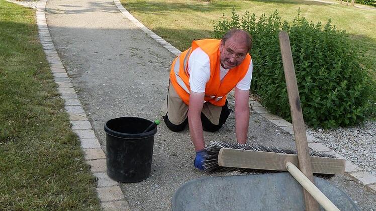 Eddi Grimm bei seiner täglichen Arbeit. Kniend zupft der "Mister Saubermann" das Unkraut aus den Wegen des Partnerschaftsplatzes heraus. Foto: Werner Reißaus