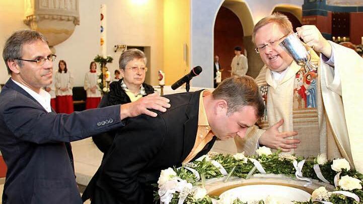 Pfarrer Thomas Ringer taufte in Adelsdorf Tino Eichler - im Hintergrund Dagmar Haas, Pastoralreferentin.