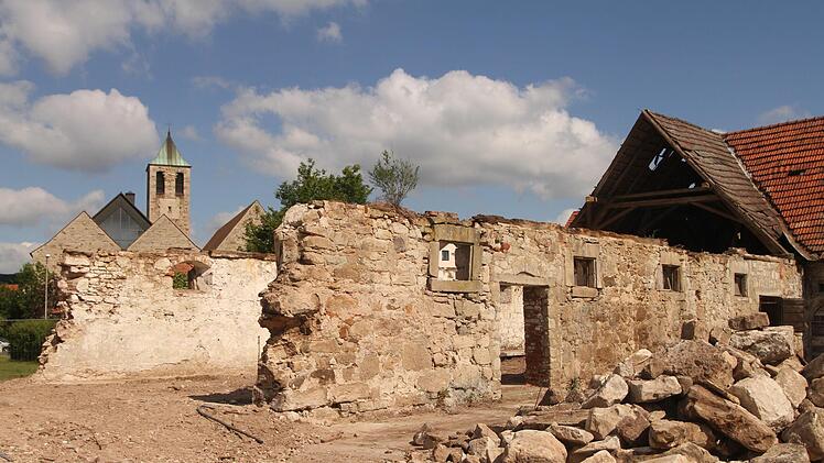 Blick auf die Mauern des ehemaligen Bullenstalles mit dem offenen Giebel und der Pfarrkirche im Hintergrund. Foto: Günther Geiling