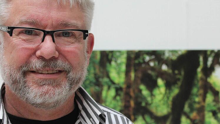 Harald Beyer zeigt seine Fotos im Landratsamt. Hinten ist ein nordamerikanischer Urwald zu sehen.   Foto: Benedikt Borst