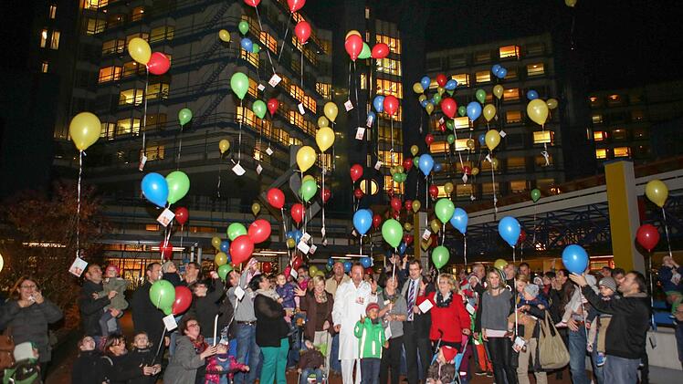 Mit guten Wünschen adressiert, lassen Eltern und ihre Kinder vor dem Klinikum bunte Luftballons in den Nachthimmel aufsteigen. Foto: RiegerPress