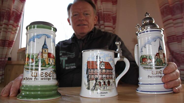 Franz Böhmer mit drei Bierkrügen, die heimatliche Motive aus Bad Staffelstein und seinem Heimatdorf Wiesen zeigen. Foto: Matthias Einwag