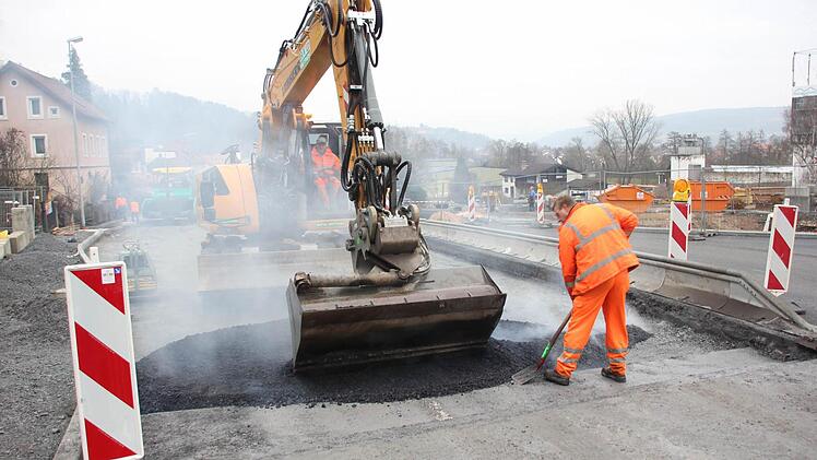 Mit der Baggerschaufel und per Hand wird der Asphalt breit gemacht. Foto: Friedwald Schedel