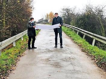 Die alte Brücke über den Bahngleisen soll nach dem Willen der Bahn abgerissen und durch ein neues Brückenbauwerk ersetzt werden, um den alten Bahnübergang "Weide" auflassen zu können. Bürgermeister Carsten Joneitis und Bauamtsleiter Markus Klarmann setzen sich vor Ort mit der Planung auseinander. Foto: Gemeinde