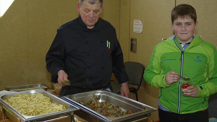 Metzgermeister Klaus Schmitt (Foto) präsentiert seine gesündere Ernährung mit einer Ofengemüsepfanne mit Penne. Nils (l.) schmeckt derweil der Fruchtjoghurt. Foto: Winfried Ehling