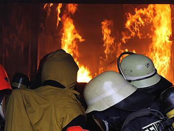 Kniend beobachten die Feuerwehrleute die Flammen im Inneren des Containers und kämpfen mit der Hitze und dem Rauch. Fotos: Dominic Buckreus