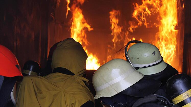 Kniend beobachten die Feuerwehrleute die Flammen im Inneren des Containers und kämpfen mit der Hitze und dem Rauch. Fotos: Dominic Buckreus