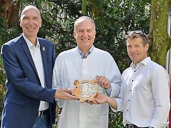 Holger Schmidt (l.) und Steffen Polster (r., beide Siemens Healthineers) &uuml;berreichten Prof. Dr. Joachim W&ouml;lfle das randvolle &bdquo;Spendenschweinchen&ldquo;.