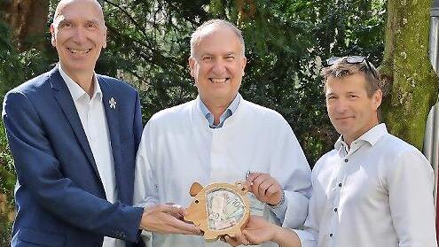 Holger Schmidt (l.) und Steffen Polster (r., beide Siemens Healthineers) &uuml;berreichten Prof. Dr. Joachim W&ouml;lfle das randvolle &bdquo;Spendenschweinchen&ldquo;.