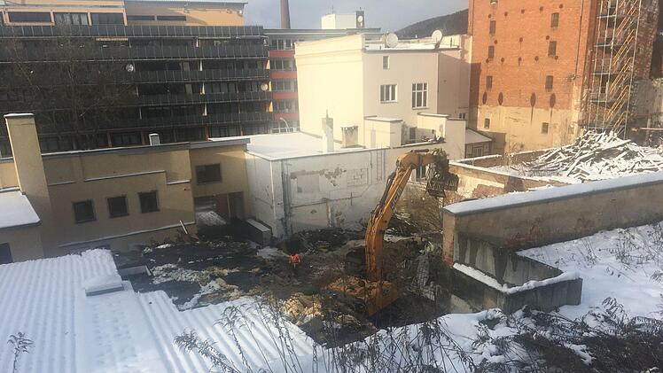 Ein Bagger räumt das Baugelände in der Pestalozzistraße 9 frei; die frühere Elektrowerkstatt Nußgräber ist schon weitgehend verschwunden. Die alte Tankstelle (links) steht noch. Die weiß gestrichenen Gebäude (Pestalozzistraße 5 und 7) in der Bildmitte bleiben stehen. Rechts der eingerüstete Backstein-Darrturm der Petzbräu, Pestalozzistraße 3.    Foto: Stephan Tiroch