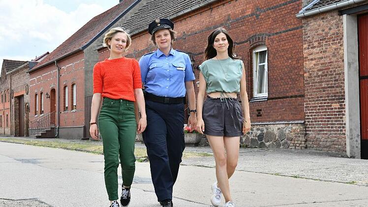 Melanie (Annett Sawallisch, Mitte) arbeitet als Polizistin im Dorf Wolfswinkel. Als ihre Freundin Lydia (Claudia Eisinger, rechts) ins Dorf zurückkehrt, löst sie ein ziemliches Chaos aus. Anja (Alina Levshin, links) möchte das unbedingt verhindern.