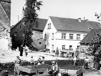 Kirchenneubau Sankt Georgskirche in Wittershausen im Jahre 1957: Neben der mehr als 700-jährigen Dorfgeschichte wurde beim großen Jubiläumsfest im Jahre 2017 auch an das 60-jährige Bestehen des neuen Wittershäuser Gotteshauses erinnert. Am alten Schulgebäude (weißes Gebäude auf dem Foto) am Kirchenvorplatz wurde nun die Metalltafel an der Fassade angebracht.
