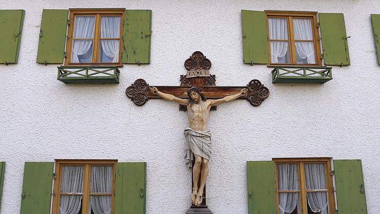 Ein großes Kruzifix hängt an der Außenwand eines Bauernhauses. In Bayern gibt es Streit um die angeordnete Aufhängung von Kreuzen in bayerischen Landesbehörden. Foto: Karl-Josef Hildenbrand/dpa