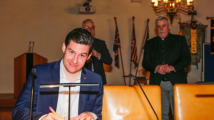 Dominik Sauerteig unterzeichnet die Annahmeerklärung, OB Norbert Tessmer (rechts) und Wahlleiter Willi Kuballa wachen im Hintergrund. Foto: Matthias Hoch