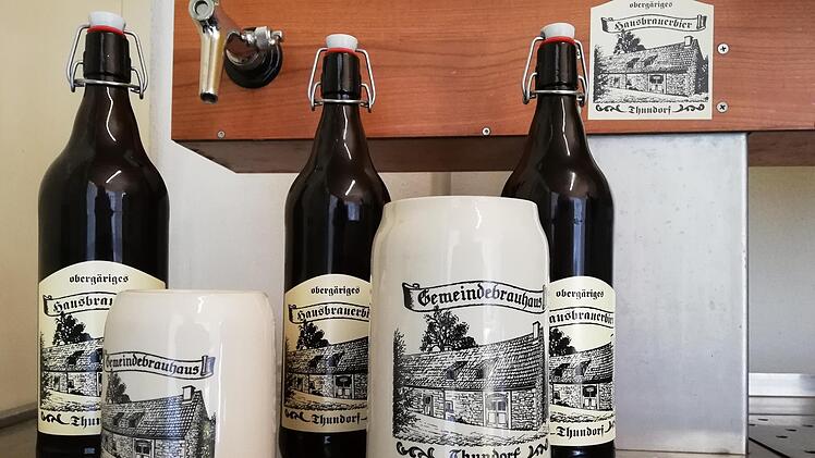 Auch eigene Krüge und Aufkleber gibt es vom Bier aus dem Thundorfer Gemeindebrauhaus. Foto: Heike Beudert