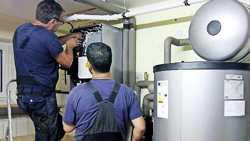 Zwei Techniker stellen eine W&auml;rmepumpe ein. Im Landkreis informiert der Verein Energiewende ER(H)langen &uuml;ber diese Heizungstechnik.