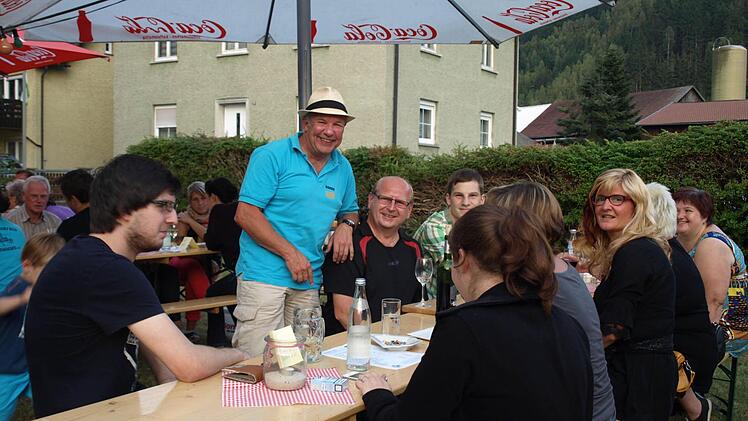 Der 1. Vorsitzende des Musikvereins Stefan "Dogde" Hümmer (steh. mit Hut) begrüßt die Gäste beim Weinfest im legendären "Heinergarten". Foto: Susanne Deuerling